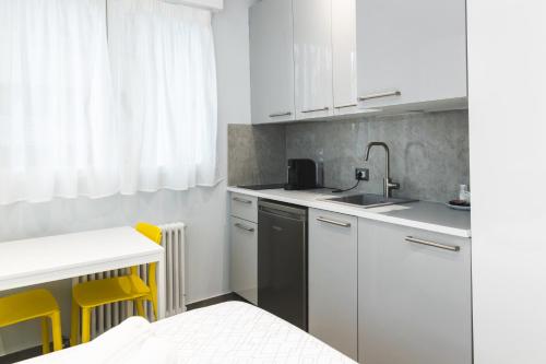 una cucina con armadi bianchi e dettagli gialli di Residenza Gioiello - Comfort & Suites a Milano a Milano