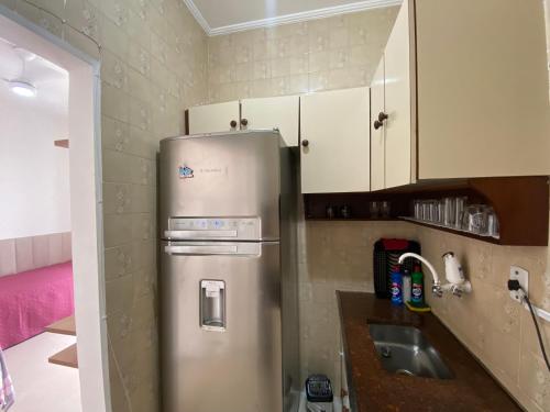 eine Küche mit einem Kühlschrank aus Edelstahl und weißen Schränken in der Unterkunft Apto Santos Gonzaga in Santos