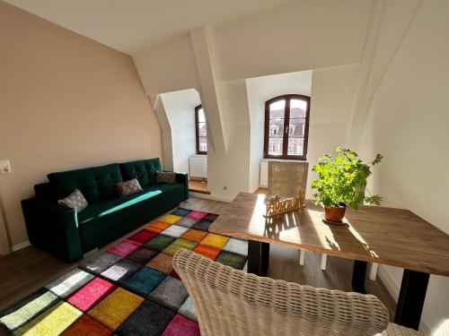 a living room with a green couch and a table at FeWos Anno 1529 in Top-Altstadtlage von Zittau in Zittau