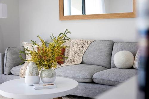 a living room with a gray couch and a table at Esplanade Elegance Seaford: Sleeps 7 in Seaford