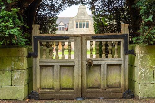 an old wooden gate with a house in the background at 2 The Winnings - Stunning Cottage on a Country Estate in Worksop