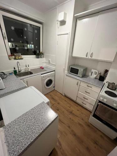 a white kitchen with a sink and a microwave at Nice Battersea Flat in London