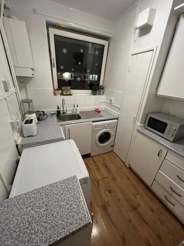 a small kitchen with a sink and a microwave at Nice Battersea Flat in London