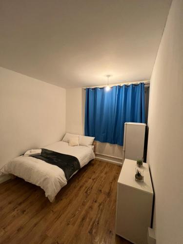 a bedroom with a bed and a blue curtain at Nice Battersea Flat in London