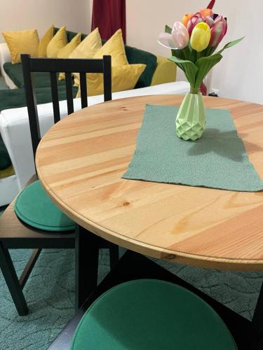 a wooden table with a vase of flowers on it at Veľký apartman in Karlova Ves
