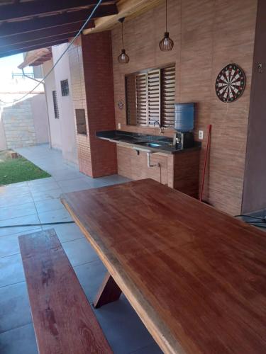 una mesa de madera en una cocina con reloj en la pared en Casa para temporada en Pirenópolis