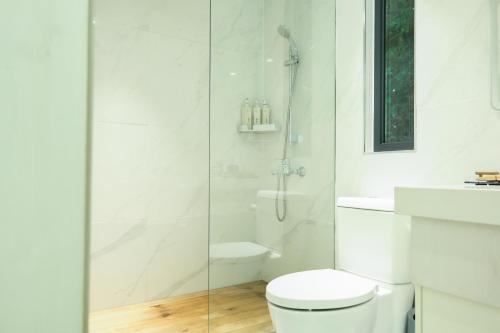 a white bathroom with a toilet and a shower at Zhumaxi Leisure Lodge in Zhangjiajie
