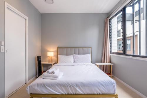 a bedroom with a bed with white sheets and a window at Westend 3 bedroom Split level Townhouse Next to River in Brisbane