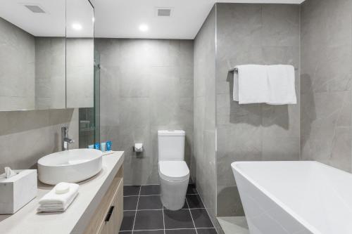 a bathroom with a white toilet and a sink at Meriton Suites Bondi Junction in Sydney