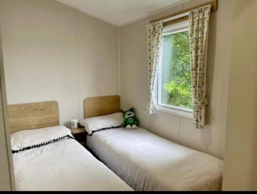two beds in a room with a teddy bear sitting between them at Talland view. Polperro in Looe