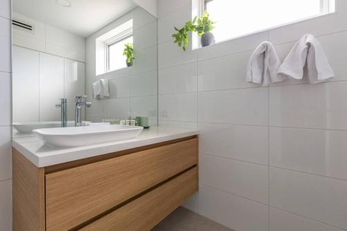 uma casa de banho branca com um lavatório e um espelho em Breezy East - A Light-filled Family Retreat em Melbourne
