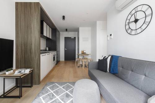 a living room with a couch and a clock on the wall at Modern and Cosy Parkland Retreat near Yarra River in Melbourne