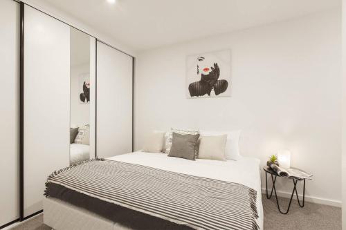 a bedroom with a large bed with white walls at Modern and Cosy Parkland Retreat near Yarra River in Melbourne