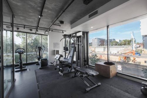 a gym with tread machines and a large window at Modern and Cosy Parkland Retreat near Yarra River in Melbourne