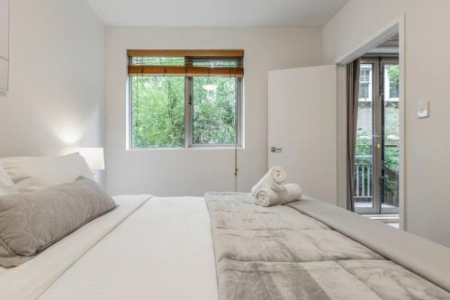 um quarto branco com uma cama grande e janelas em Experience the St Kilda Vibe from a Cosy Retreat em Melbourne