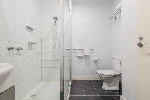 a white bathroom with a shower and a toilet at Inner City Living in a Modern Slice of History in Melbourne