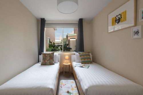 twee bedden in een kleine kamer met een raam bij Spacious Suburban Comfort Perfect for Families in Melbourne