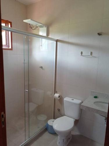 a bathroom with a toilet and a glass shower at Agradável Casa de Campo, recém construída. in Divisa