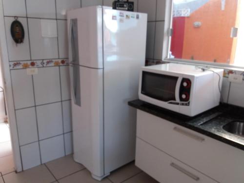 a kitchen with a white refrigerator and a microwave at Sol e Mar 850mts do mar Ingleses Satinho in Florianópolis