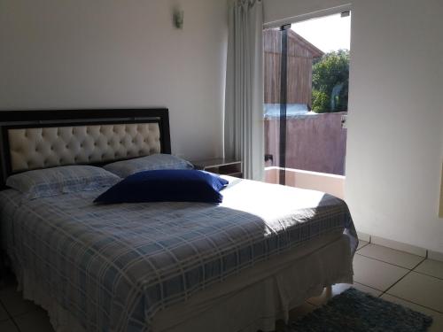 a bedroom with a bed with a blue pillow on it at Sol e Mar 850mts do mar Ingleses Satinho in Florianópolis