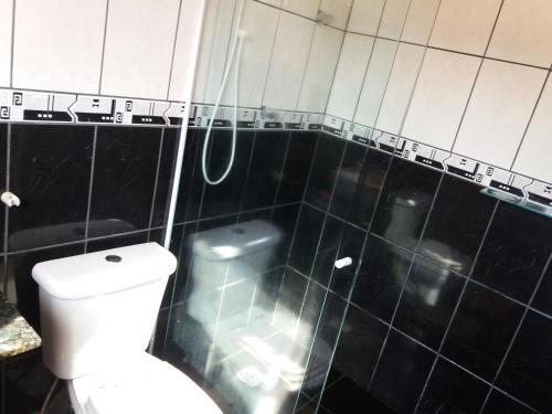 a black tiled bathroom with a toilet and a shower at Sol e Mar 850mts do mar Ingleses Satinho in Florianópolis