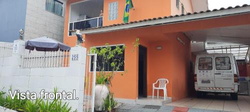an orange house with a chair outside of it at Sol e Mar 850mts do mar Ingleses Satinho in Florianópolis