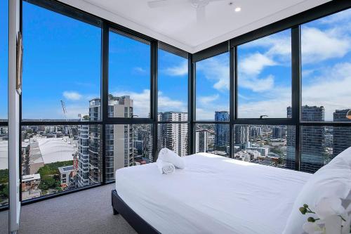 a bedroom with a white bed and large windows at Soaring Skyline on Southside at Resort-Style Stay in Brisbane