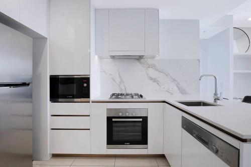 a white kitchen with a stove and a microwave at Soaring Skyline on Southside at Resort-Style Stay in Brisbane