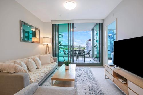 a living room with a couch and a flat screen tv at 'Riverfront Flow' Poolside and Portside in Hamilton in Brisbane