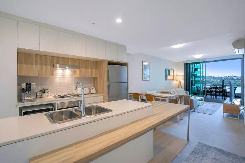 a kitchen with a sink and a living room at 'Riverfront Flow' Poolside and Portside in Hamilton in Brisbane