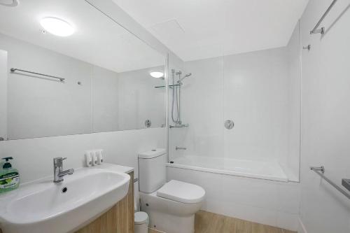 a white bathroom with a toilet and a sink at 'Riverfront Flow' Poolside and Portside in Hamilton in Brisbane