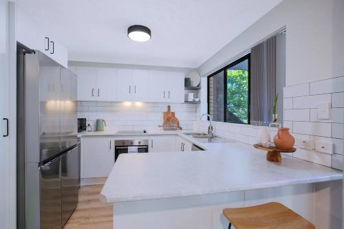 a white kitchen with a large white counter top at Toowong Village Tranquility - A Slice of Brisbane in Brisbane