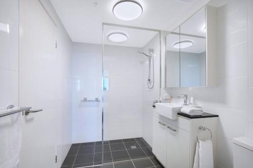 a white bathroom with a shower and a sink at Fall in Love with Waterfront Resort-style Living in Brisbane