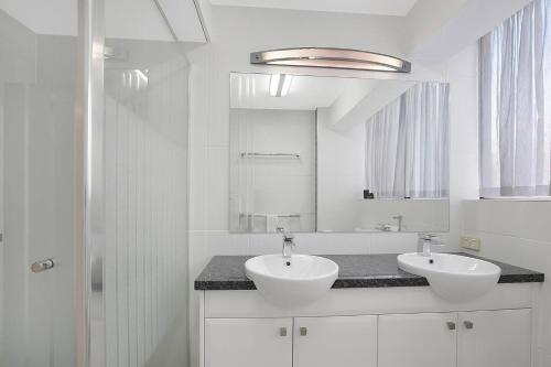 a white bathroom with two sinks and a mirror at 'Riverside Terrace' Inner-city Retro-chic with Pool in Brisbane