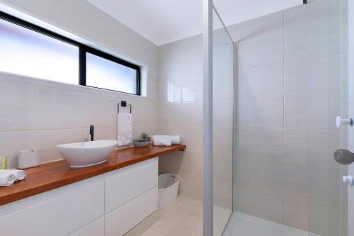 a bathroom with a sink and a glass shower at Tropical Dreaming in the Heart of Indooroopilly in Brisbane