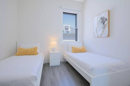 ブリスベンにあるCity Centre Comfort - Your Home in Vibrant Brisbaneの白い部屋で、ベッド2台、窓が備わります。