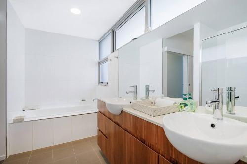 a bathroom with two sinks and a large mirror at The Sun Catcher - A Trendy South Brisbane Terrace in Brisbane