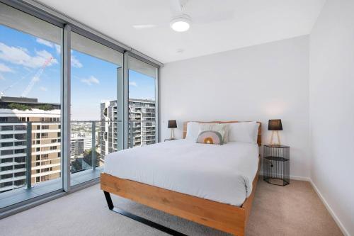 a bedroom with a bed and large windows at The Skyring - Effortless Resort-style Living in Brisbane