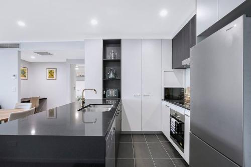 a kitchen with white cabinets and a black counter top at The Skyring - Effortless Resort-style Living in Brisbane