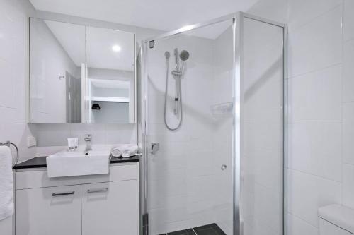 a white bathroom with a shower and a sink at The Skyring - Effortless Resort-style Living in Brisbane