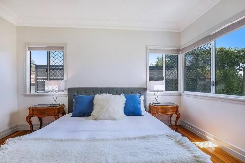 een witte slaapkamer met een groot bed en 2 tafels bij Nundah's Lush Haven - Serene Family Townhouse Escape in Brisbane