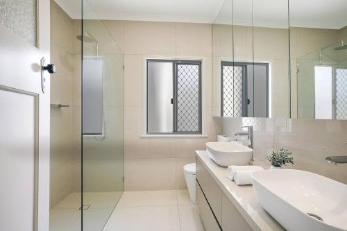 een badkamer met een wastafel, een toilet en een douche bij Nundah's Lush Haven - Serene Family Townhouse Escape in Brisbane