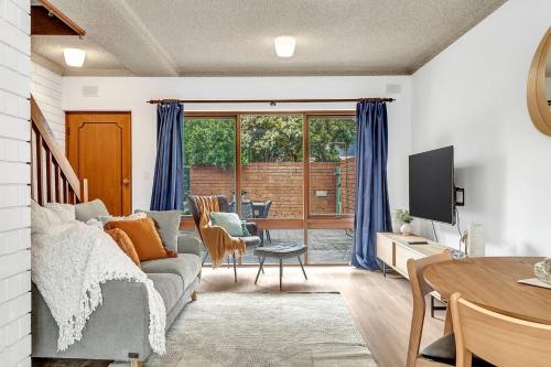 a living room with a couch and a table at Brightly Beachside - Where Jetty Rd meets the Ocean in Adelaide
