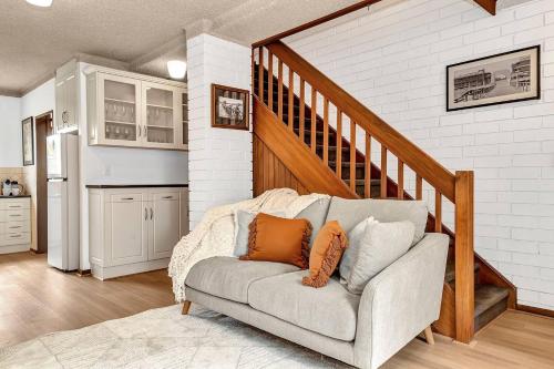 a living room with a couch and a staircase at Brightly Beachside - Where Jetty Rd meets the Ocean in Adelaide