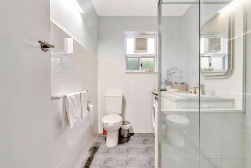 een witte badkamer met een toilet en een wastafel bij Adventure Awaits - Footsteps from West Beach in Henley Beach South