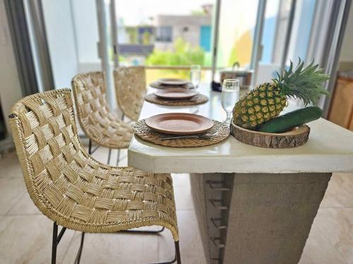 a table with a pineapple and plates and chairs at 2BdR -Rocks at Mikasa- Near Beach, Pool, King Beds, AC, Fast Wifi in Puerto Escondido