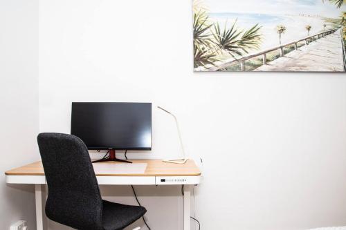 a computer sitting on a desk with a chair at Seaside Smart Home - Coastal Chic at Henley Beach in Adelaide