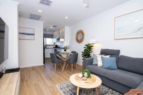 a living room with a couch and a table at Seaside Smart Home - Coastal Chic at Henley Beach in Adelaide