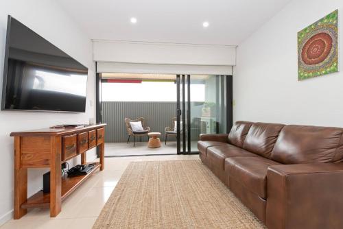 a living room with a brown leather couch and a flat screen tv at Perfect Prospect Among City's Dining Hotspots in Adelaide