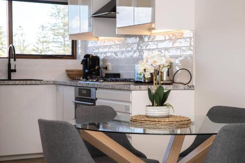a kitchen with a glass table and some chairs at Seaside Smart Home - Coastal Chic at Henley Beach in Adelaide